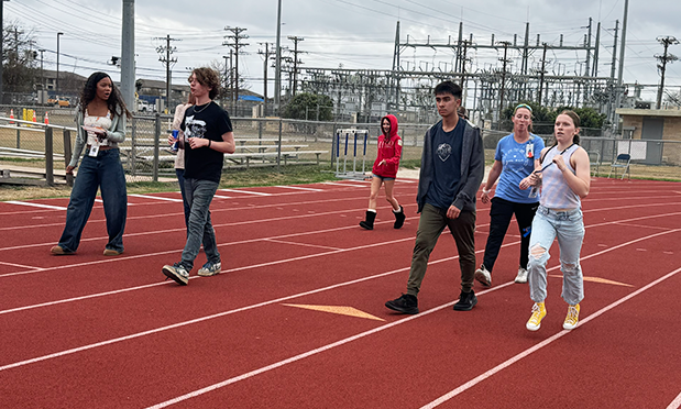 high school students walk on a running track