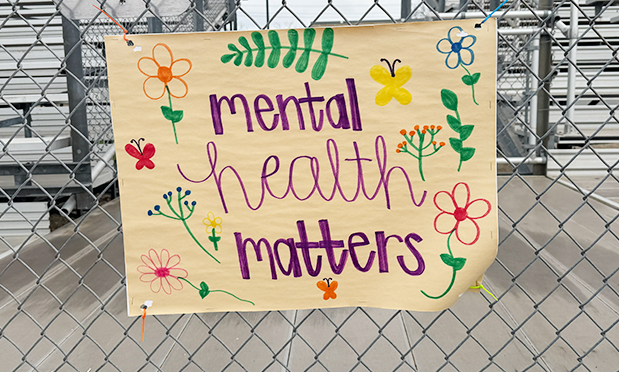 a student-produced sign on sepia paper reads "mental health matters" in a bold, scriptive font. around the text are assorted flowers, leaves, and butterflies.