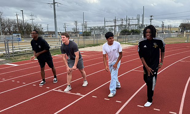 four high school boys line up for a mock 100-meter dash