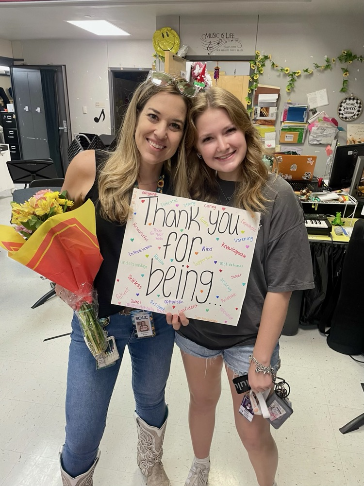 miss Bryan posing with Kinsley who is holding a thank you sign flowers