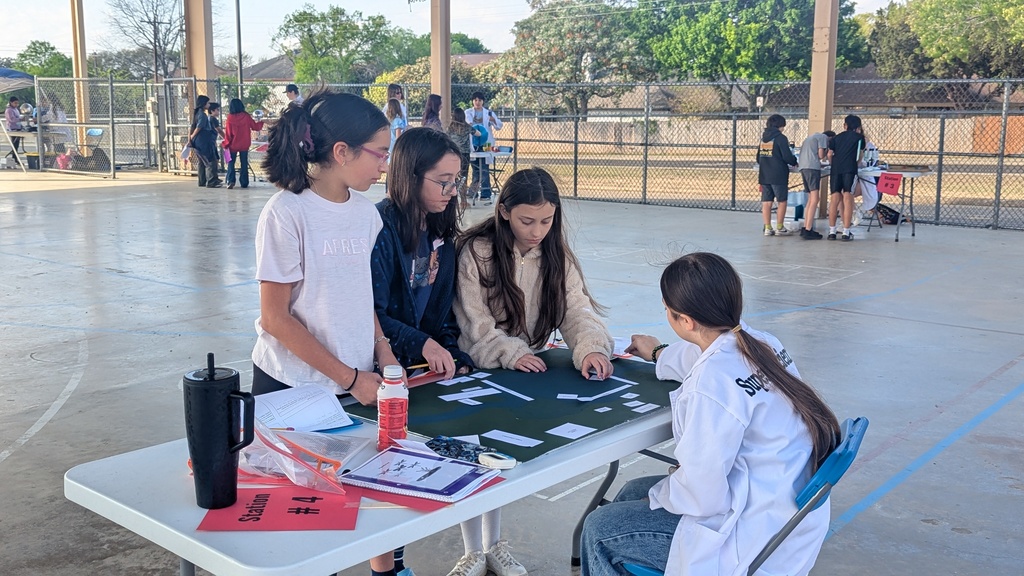 girls doing a paper activity under pavilion