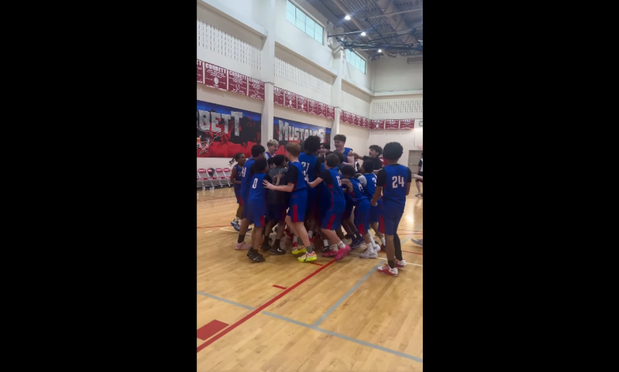 baskeball players circle around student to celebrate winning shot