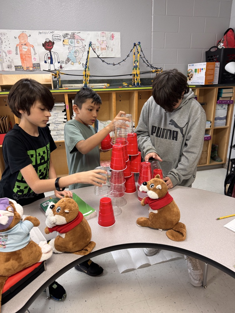 Three boys building their cup stack