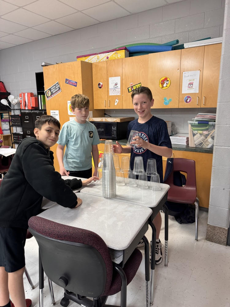 Three boys posing and building their cups stack
