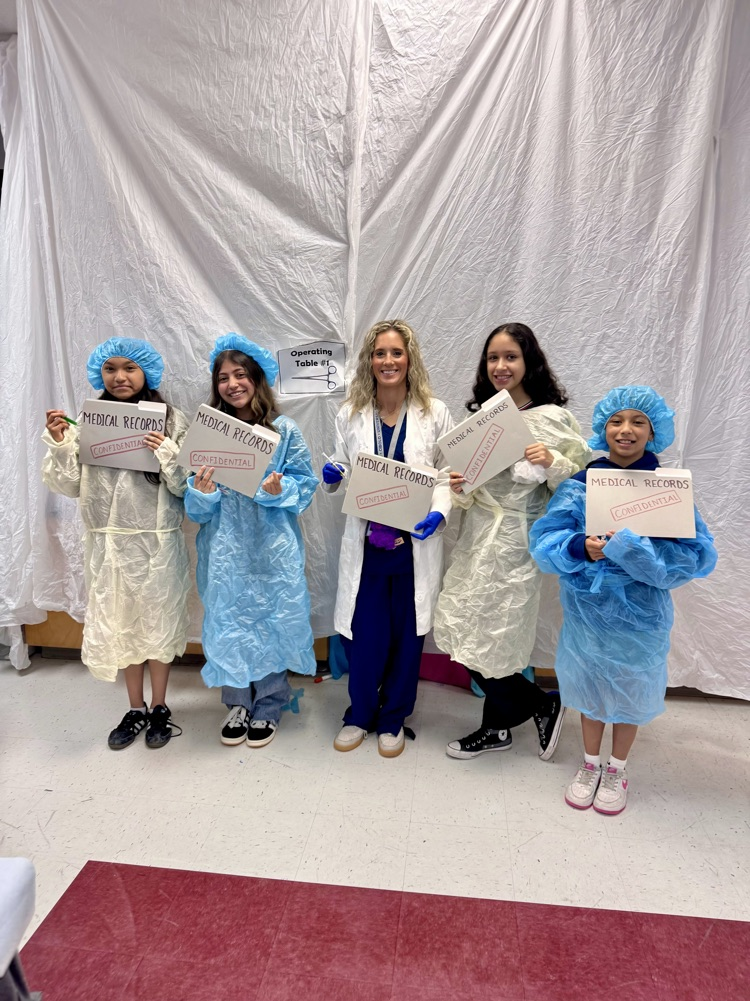 students are all dressed in surgical operating costumes on a white surgical background drop in their classroom Post with Miss Housley