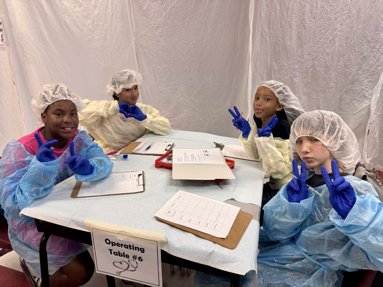Students are working at a table, wearing their operating costume costumesm