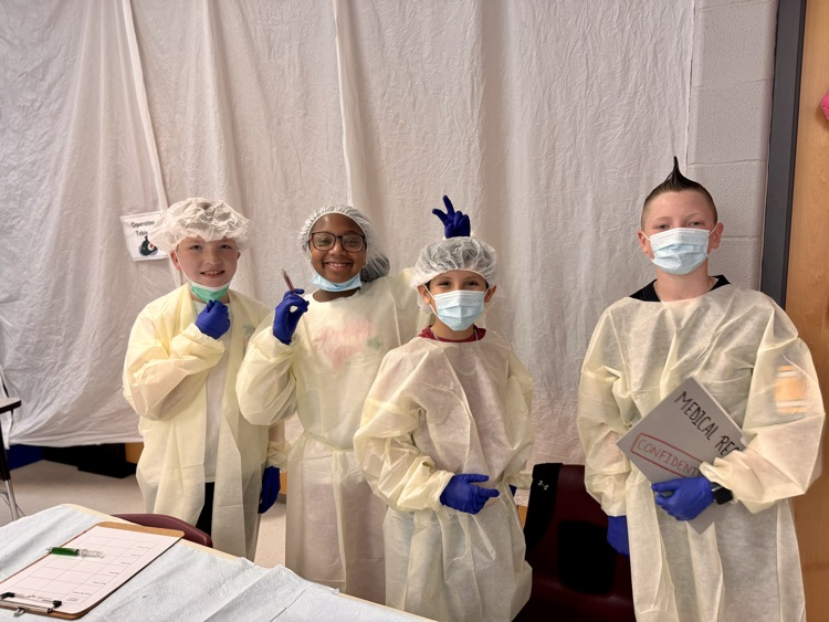 A bunch of students in their operating costumes posing in front of a white backdrop