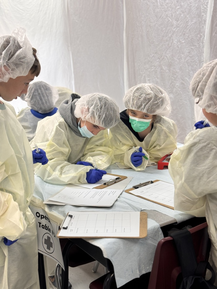 A few students working at a table together in their operating costume