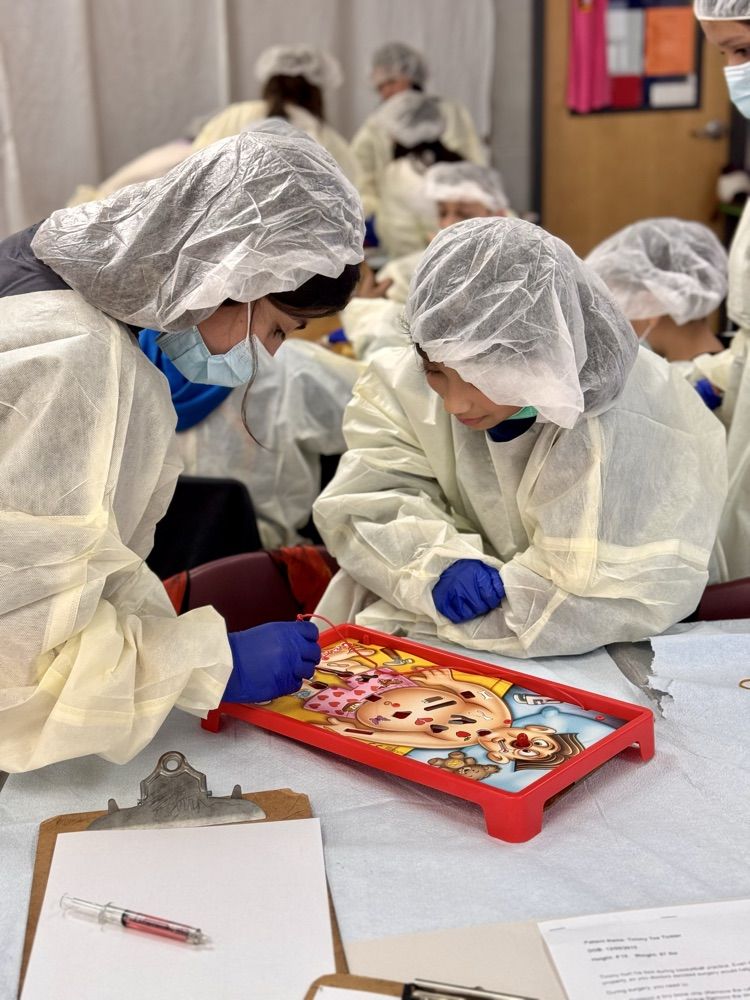 A few students leaning over the game of operation in operating costumes