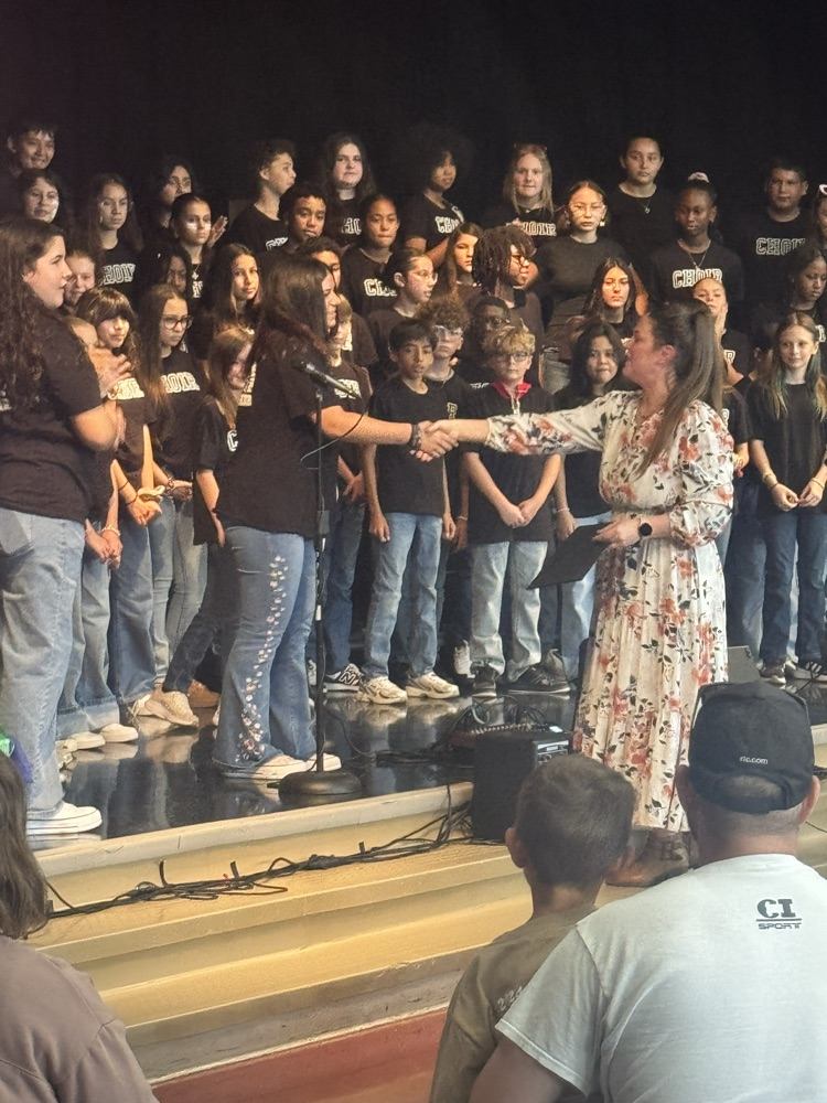 The acquire is all up on the stage while Miss Alvarado shakes a student’s hand, giving her an award