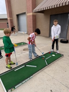 students golfing on a mini golf course