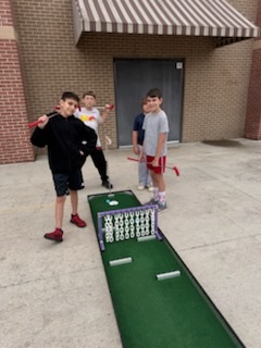 Students golfing on a mini golf course outside