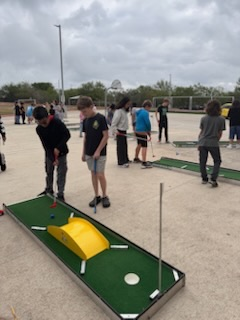 Students golfing with a yellow ramp