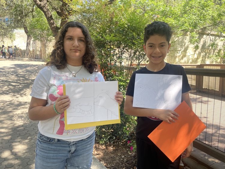 A girl and a boy holding up their sketches of animals