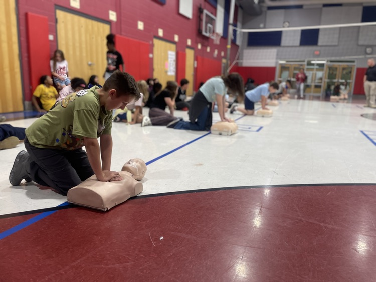 students practicing CPR on dummies in the gym