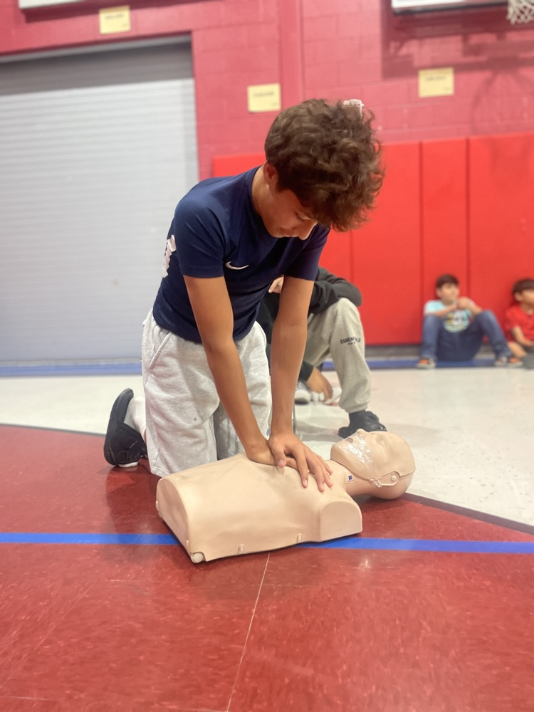 students practicing CPR on dummies in the gym