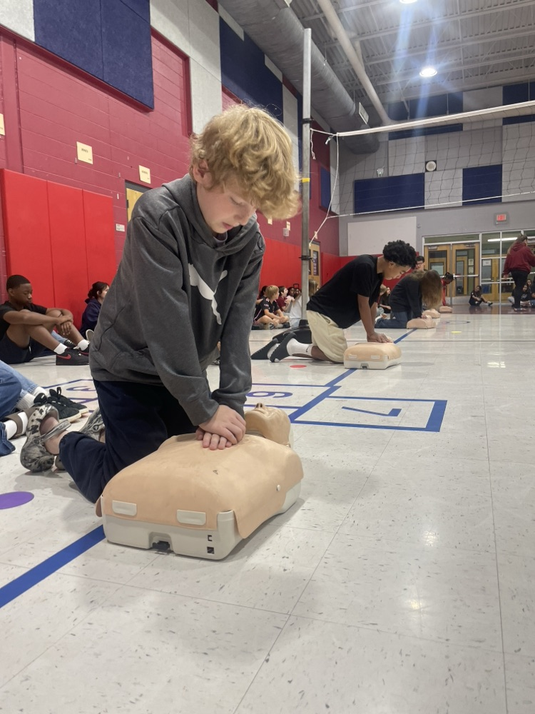 students practicing CPR on dummies in the gym