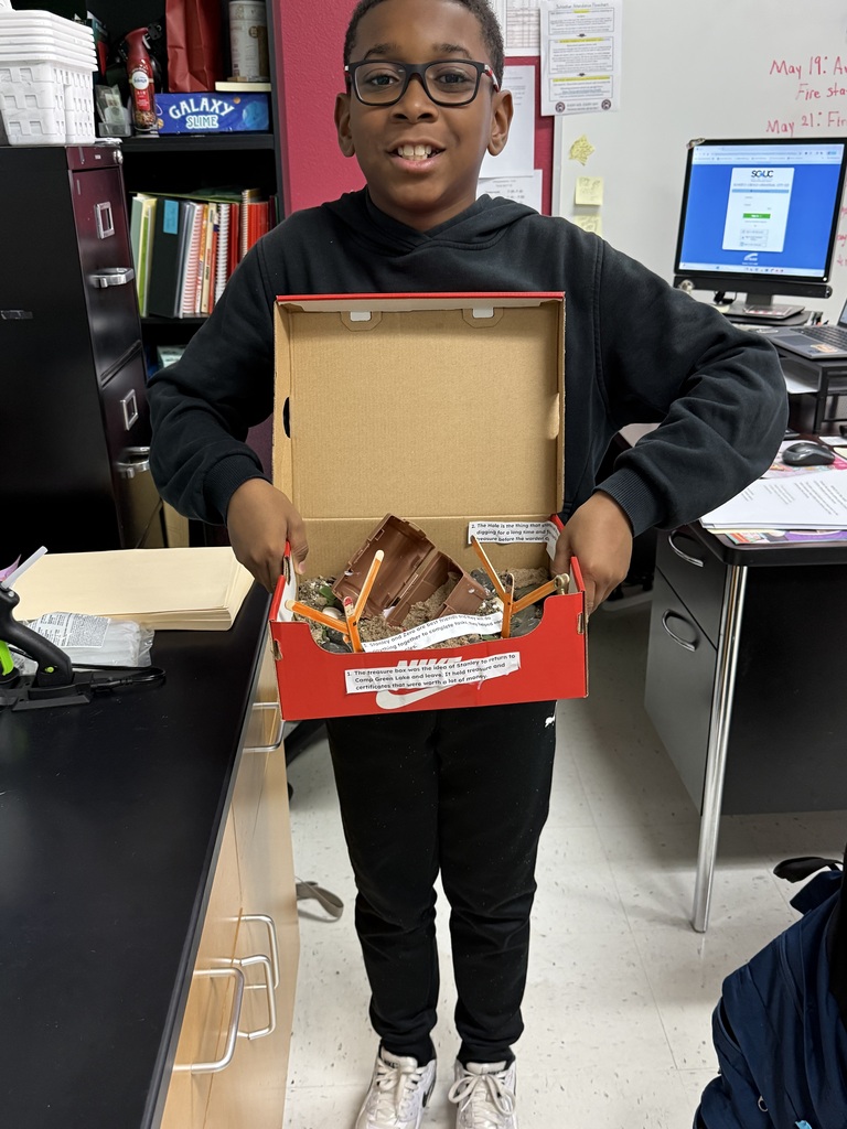 boy holding his shoe box model of a scene in the book Holes