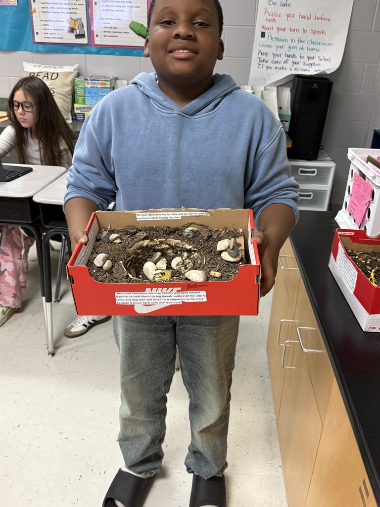 boy holding his shoe box model of a scene in the book Holes
