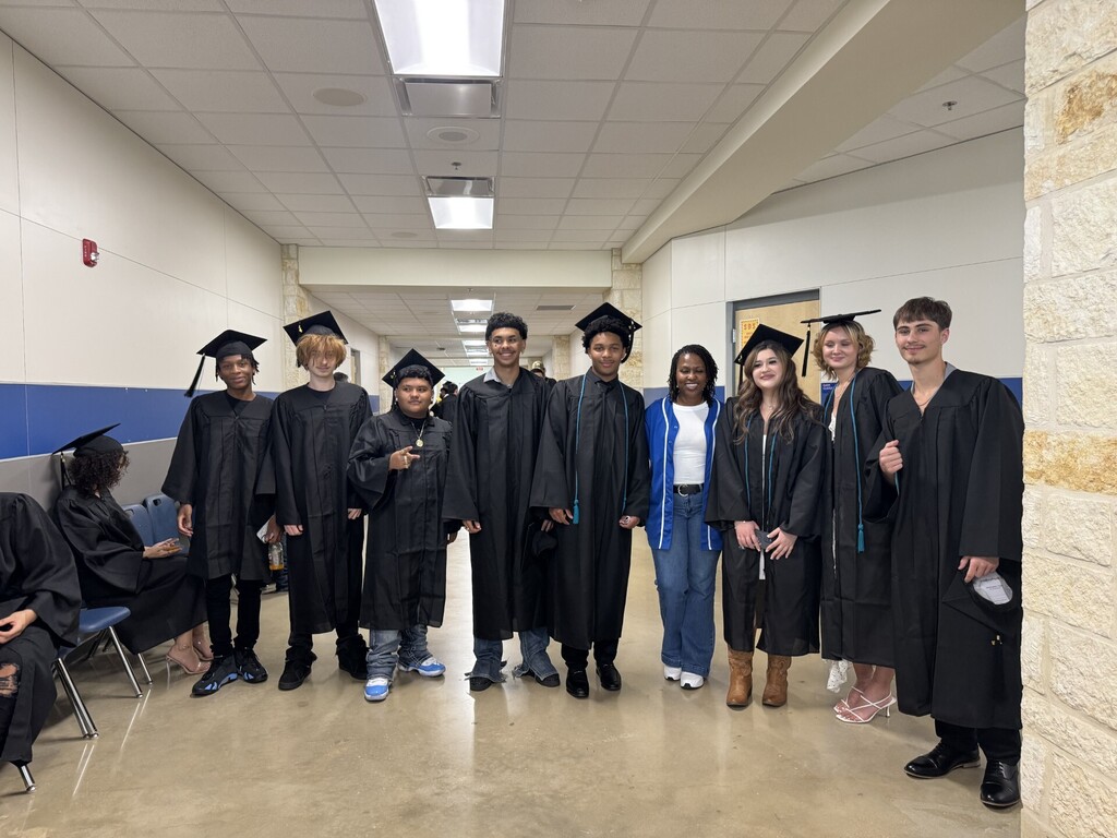counselor posing for picture with several high school graduates ready to walk the stage