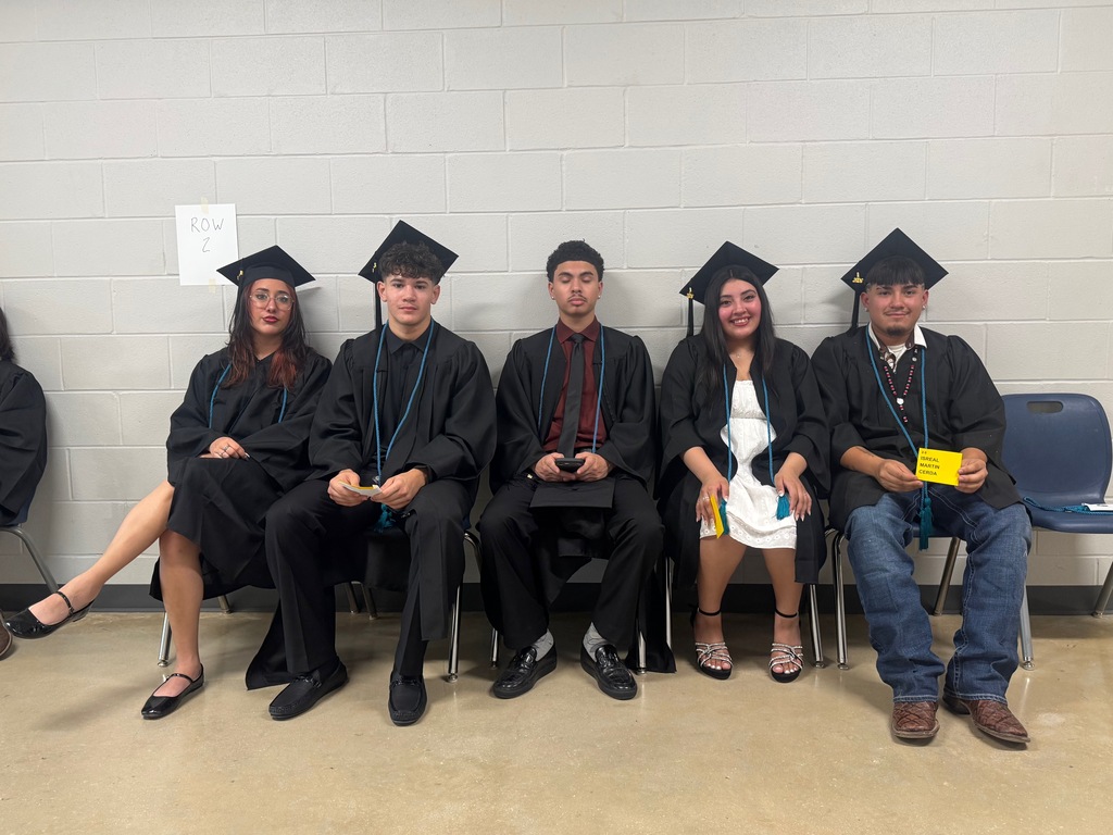 a group of students sitting down waiting for graduation walk