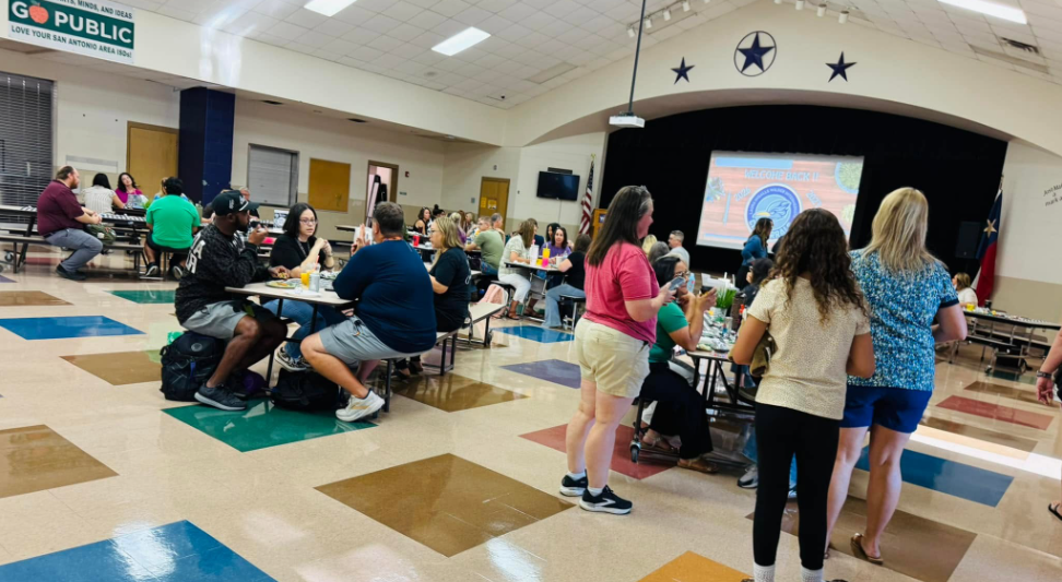 some teachers standing and some teachers sitting and eating