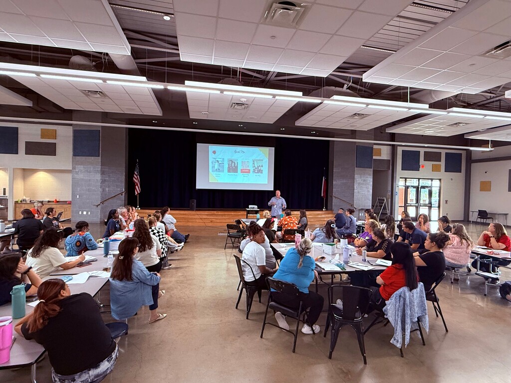 Teachers in cafeteria in a meeting.