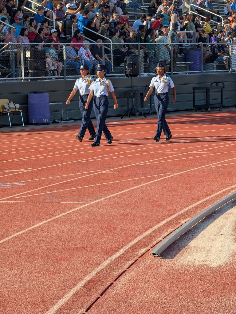 cadets in blue marching in front of a crowd