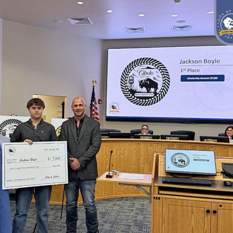 student holding. check and standing in front of winning design