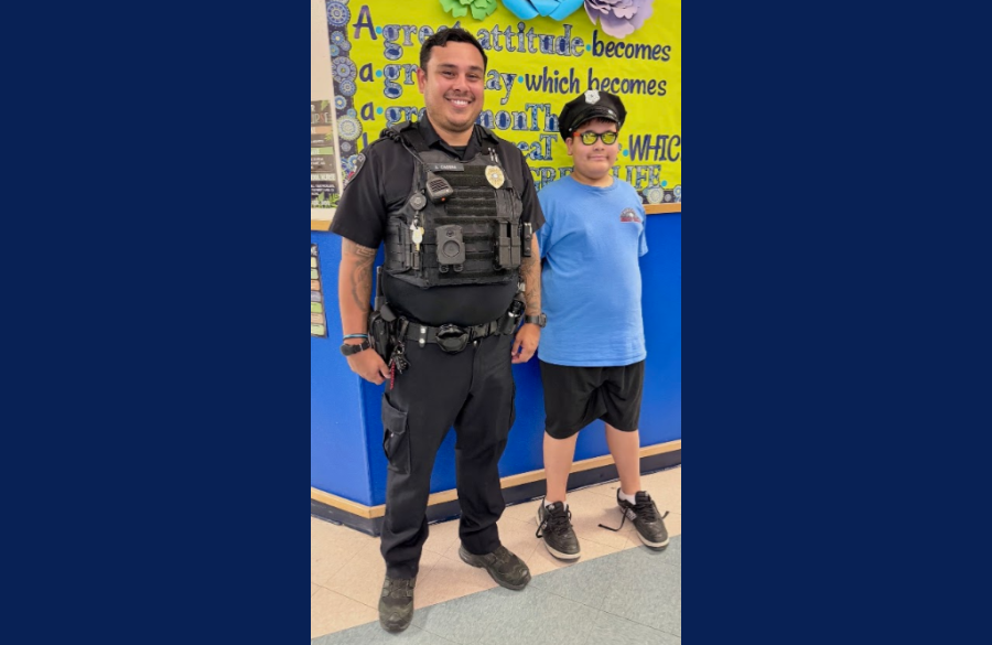 picture of a student standing next to our SRO with the SRO's hat on