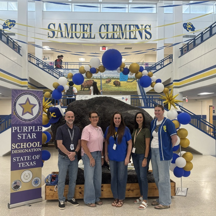 teachers standing next to purple star school banner