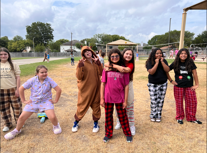 a group of girls outside at recess posing for the camera