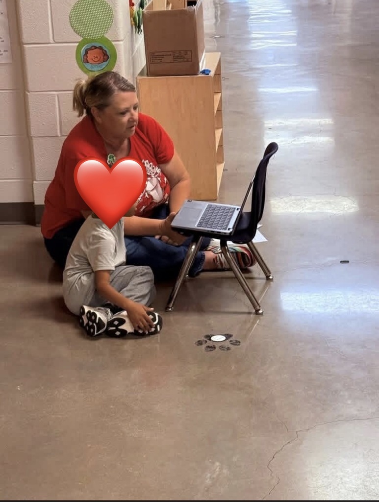 Teacher with student sitting on the ground.