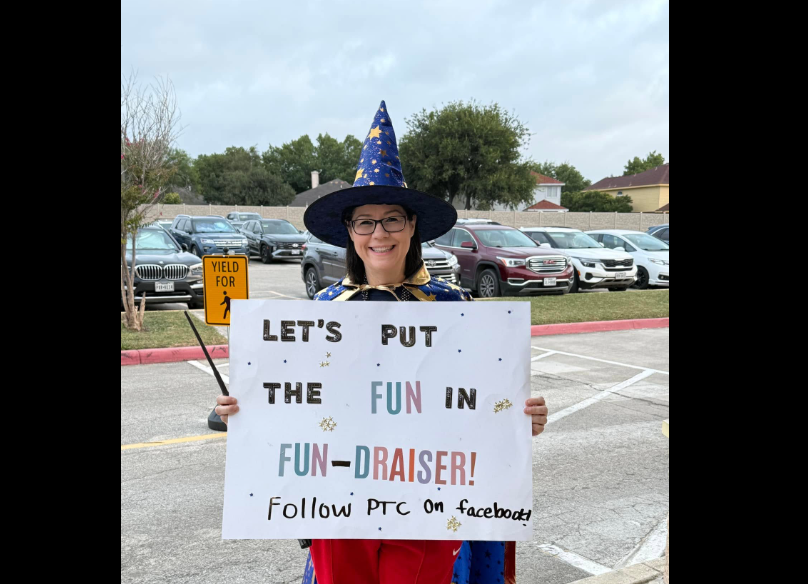 mrs. Jackson holding a fundraising sign dressed as a wizard.