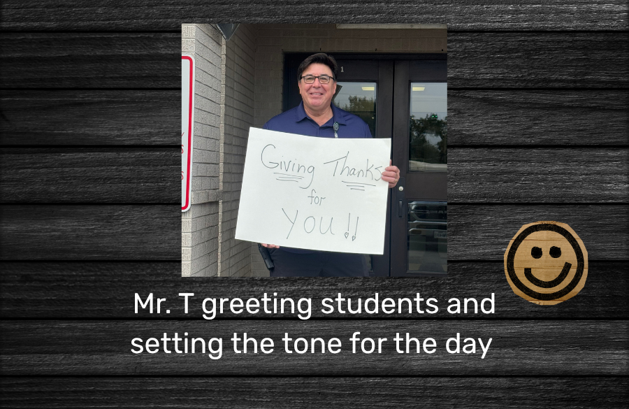 Mr. T, the principal, greeting students and setting the tone for the day holding up a sign that says "Giving thanks for you"