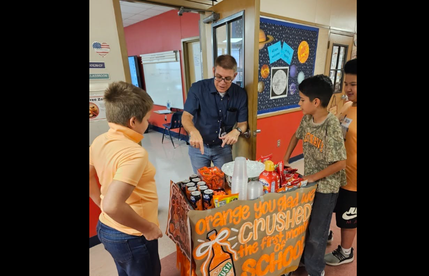 Three ALE students pushing an orange cart with snacks to Mr. Kreinhops room