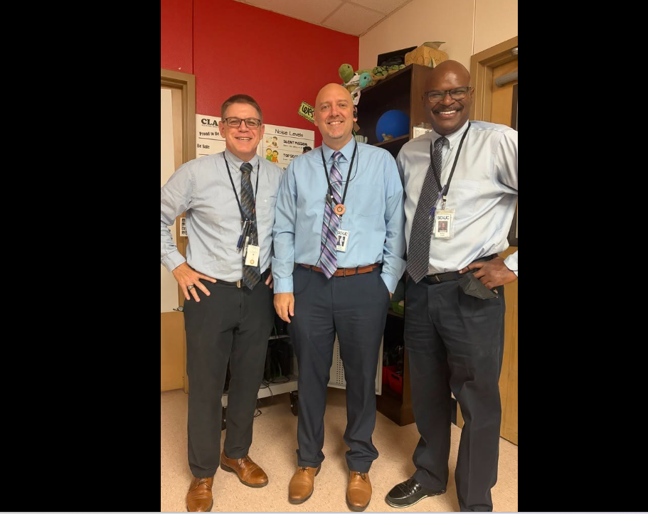 Three male staff members all wearing collared shirts, ties, and slacks