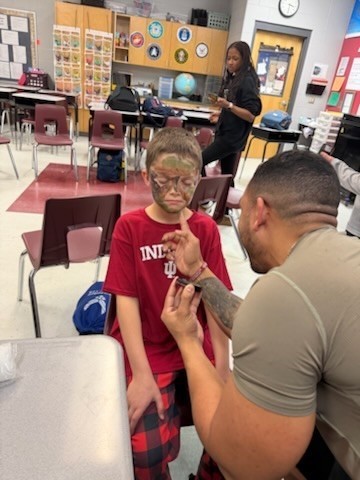 parent  painting camouflage on a studnet
