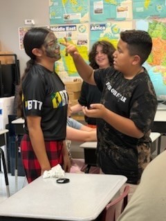 2 kids painting camouflage on each other