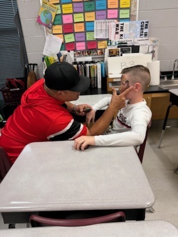 dad  painting camouflage on son