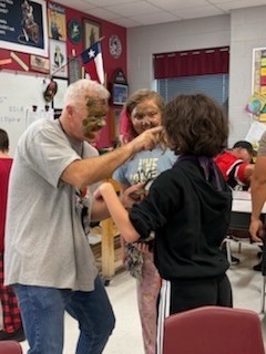 mr. jones  painting camouflage on a student