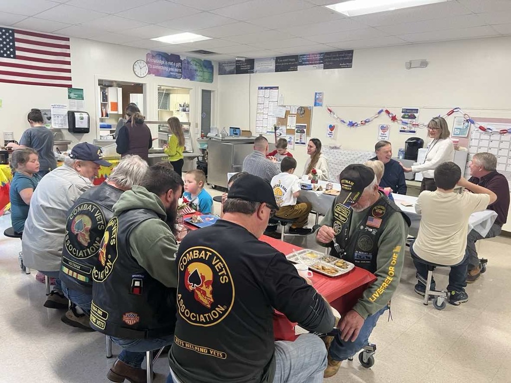 Veterans and students seated at tables. 