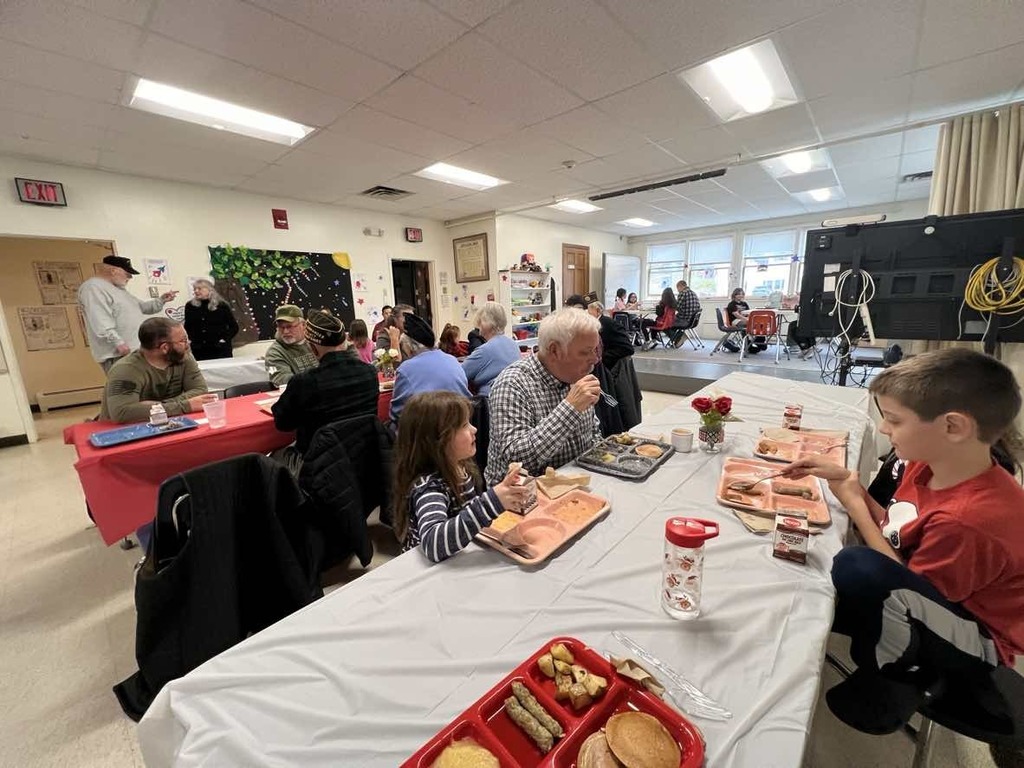 Veterans and students seated at tables. 