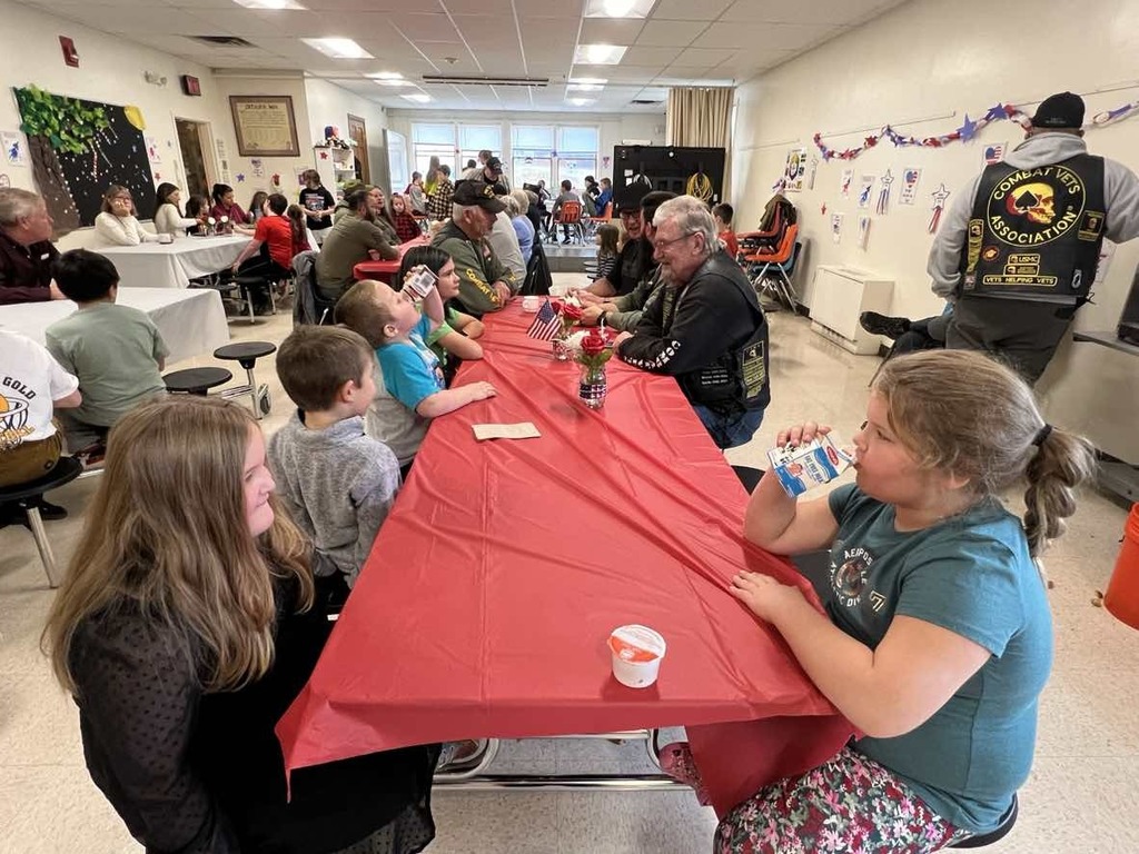 Veterans and students seated at tables. 