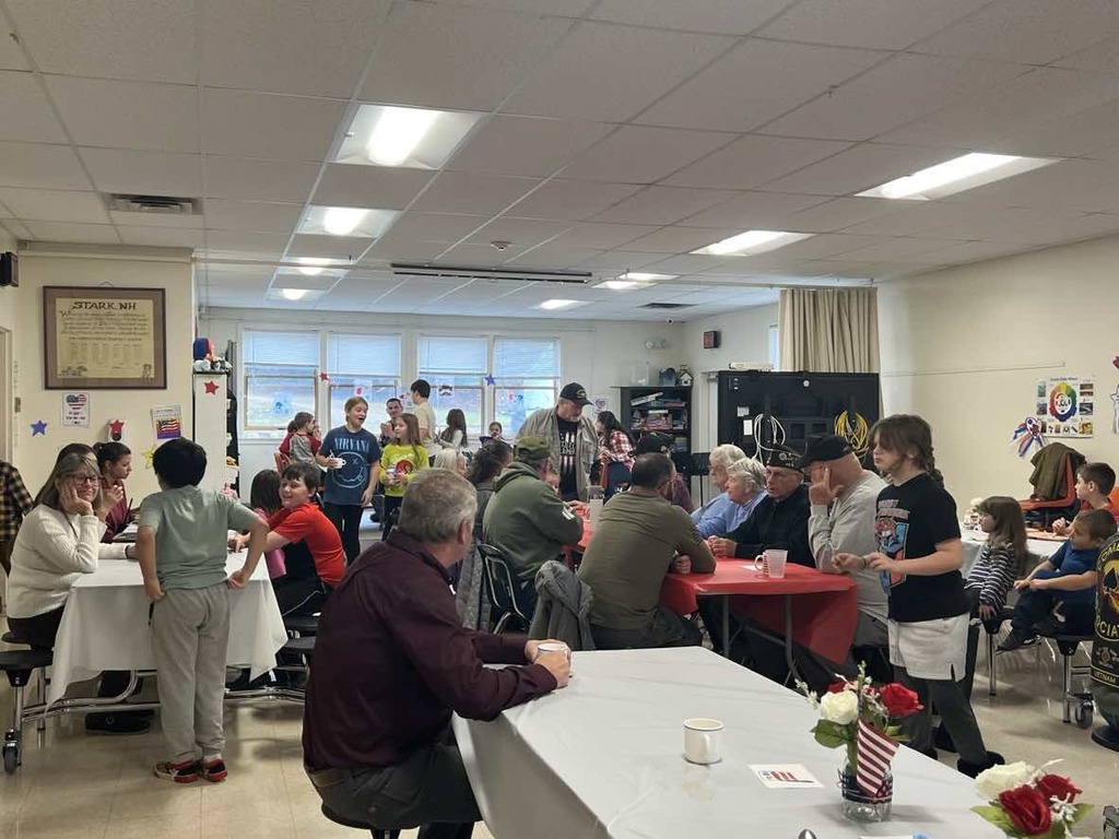 Veterans and students seated at tables. 
