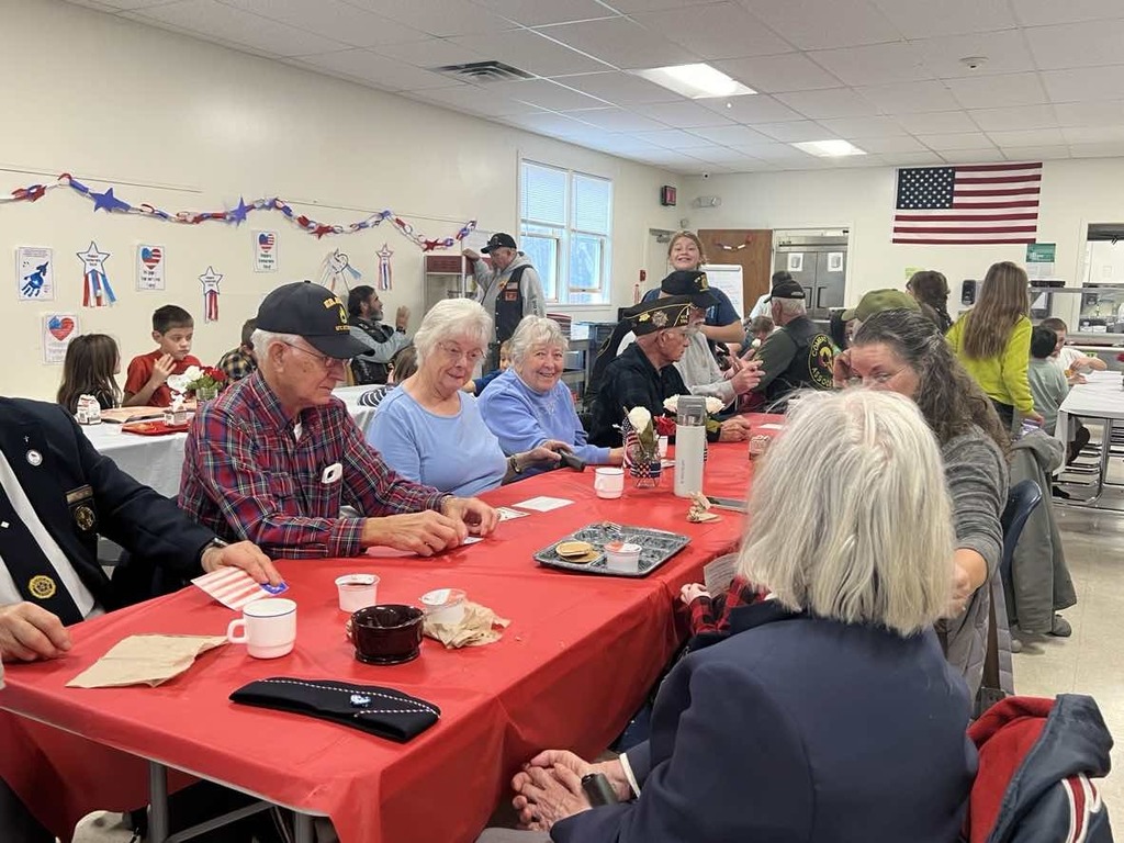 Veterans and students seated at tables. 