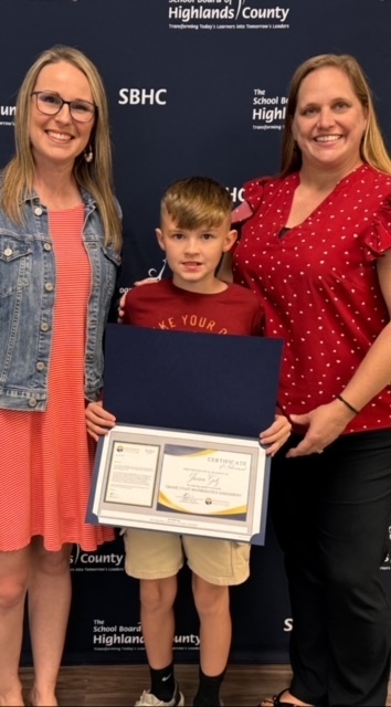 Student standing with principals receiving awards