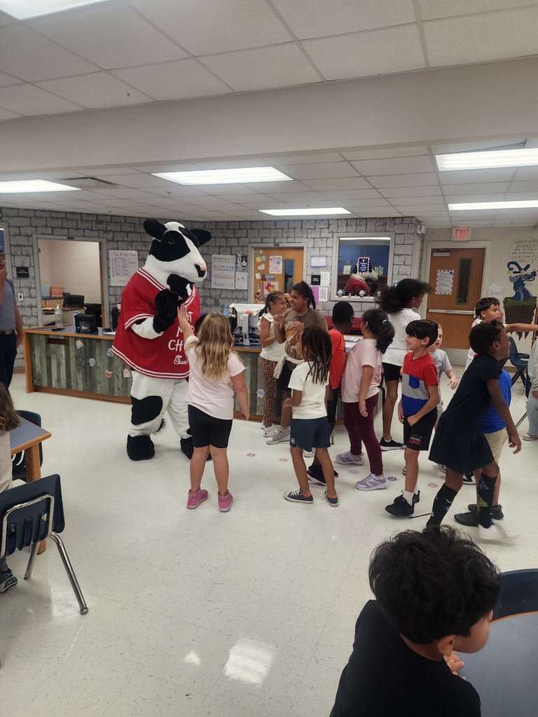 Chick Fil A cow visiting MES daycare as part of the company Million Book give away. Students and cow present in the pictures.