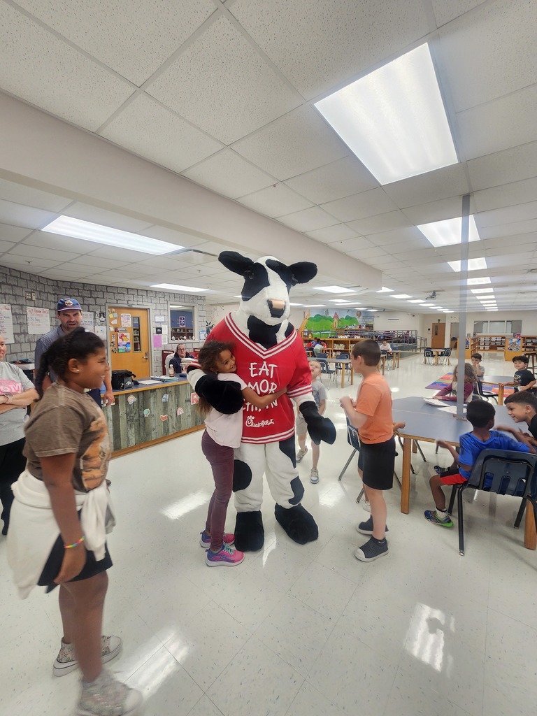 Chick Fil A cow visiting MES daycare as part of the company Million Book give away. Students and cow present in the pictures.