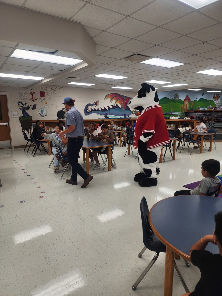 Chick Fil A cow visiting MES daycare as part of the company Million Book give away. Students and cow present in the pictures.
